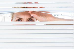 Woman Peeking through the window blinds