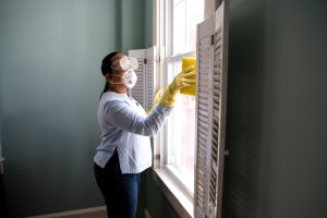 Woman with facemask cleaning the window