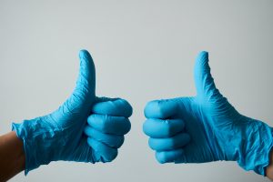 Hands in blue gloves giving a thumbs up